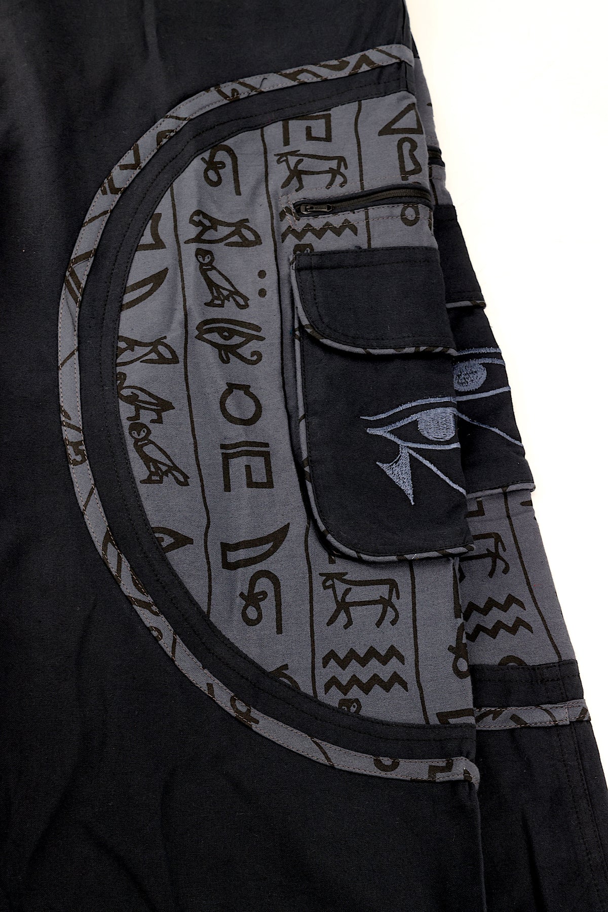 Close-up of intricate Eye of Ra embroidery on natural cotton fabric.