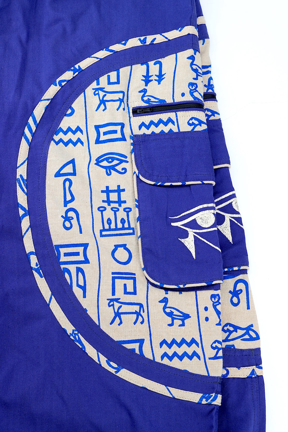 Close-up of intricate Eye of Ra embroidery on natural cotton fabric.