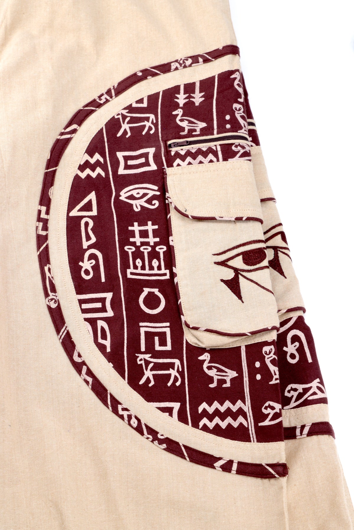 Close-up of intricate Eye of Ra embroidery on natural cotton fabric.