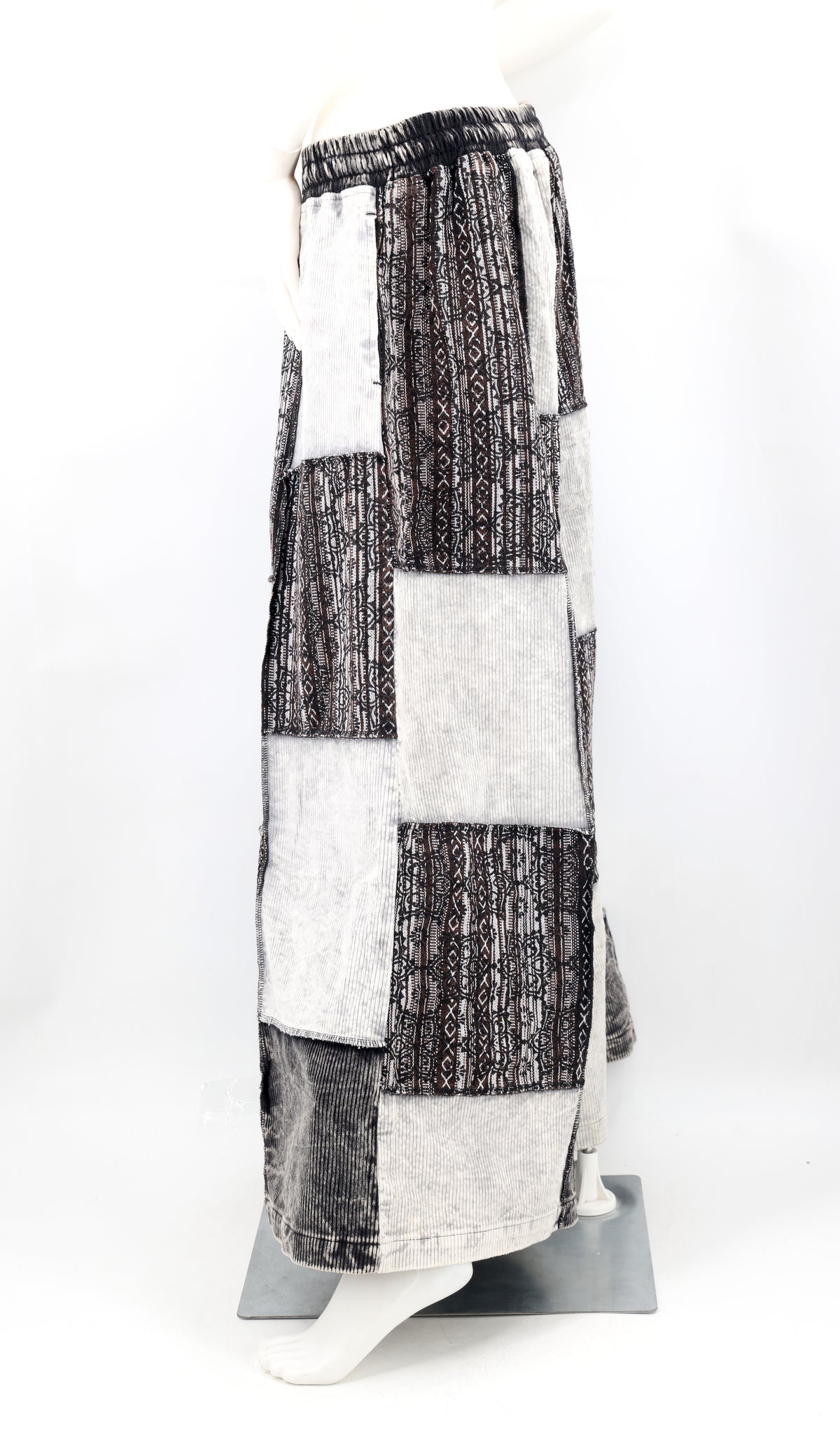 Pants with a black and white patchwork pattern on a mannequin against a white background