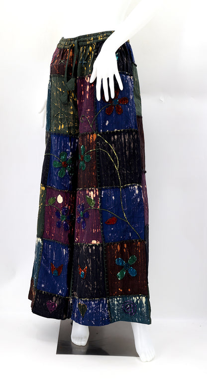 Detailed view of artisan hand embroidery and patchwork craftsmanship on natural cotton trousers